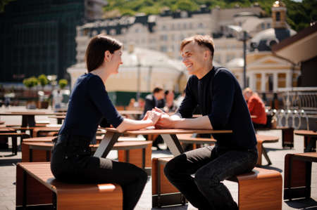 Young, happy couple smiling and holding hands across the table at a restaurant. Horizontally framed photo.の写真素材