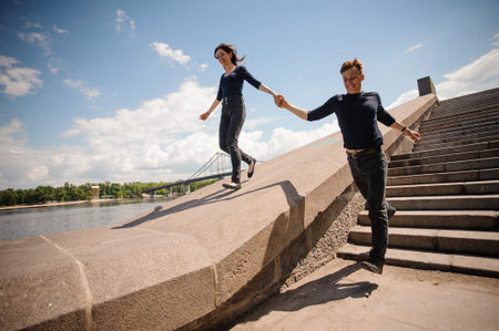 Happy young couple holding hands and running down the stairs in summer