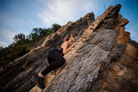 A young woman climbing on the rock. photo from the groundの写真素材