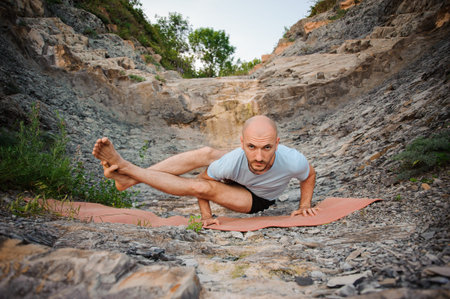 Young man doing an ashtavakrasana. Hand standing variant
