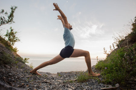 bold man doing yoga on the stone nearby ocean