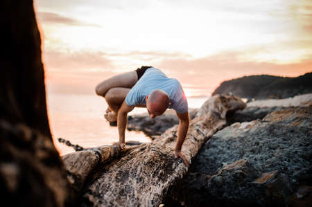 Handstand yoga pose by man on the beach near the ocean , sunsetの写真素材