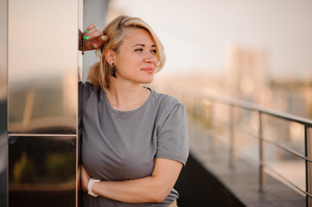 Pretty blonde woman standing on the roof top. not looking in camera