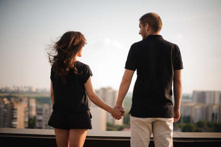 couple from behind holding hands looking on city viewの写真素材