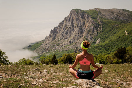 Young girl doing yoga fitness exercise outdoor in mountains landscape.の写真素材