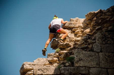 Young female rock climber climbing challenging route no face