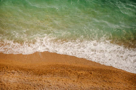 Soft sea wave on a sandy beach and pebble beach, top viewの写真素材