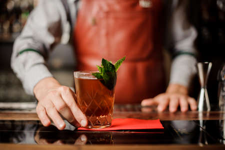 Barman holds a cocktail with mint in his handの写真素材