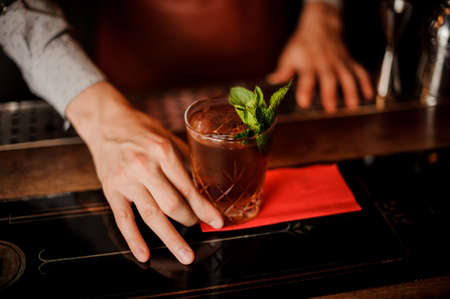 Barman holds a cocktail with mint in his hand. No faceの写真素材
