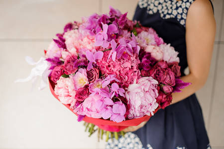 Bright and beautiful bouquet of colorful pink flowers in woman hands no face close upの写真素材