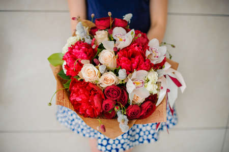 Florist holding a bouquet of beautiful and colorful red and white flowers in hands no face close upの写真素材