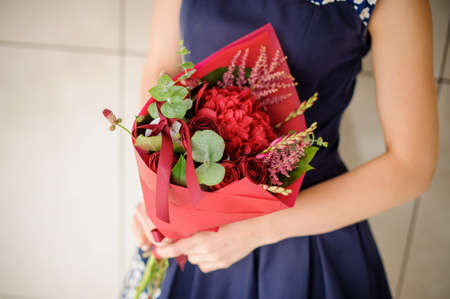 Woman hands holding a little red bouquet of flowers on a bright background no faceの写真素材