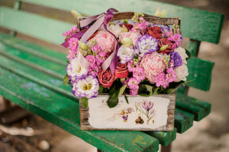 Beautiful composition of colorful pink and purple flowers standing on the green bench close upの写真素材