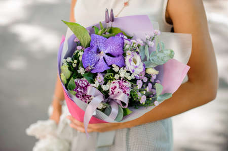 Woman hands holding a beautiful purple composition of flowers on a bright background no face close upの写真素材