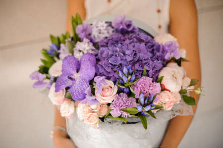 Hands with a lovely purple composition of flowers on a bright background no face close upの写真素材