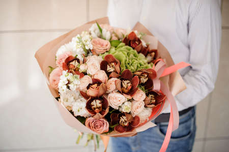 Man in striped shirt holding a pretty bouquet of flowers on a bright background no faceの写真素材