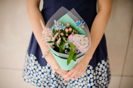 Pretty little bouquet of gentle and beautiful flowers in woman hands no face close upの写真素材