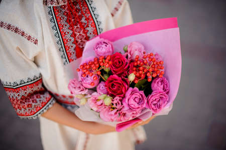 Ukrainian girl holding a pretty little bouquet of beautiful pink flowers no face close upの写真素材
