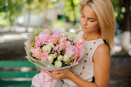 Pretty woman holding a beautiful and soft composition of flowers on a bright background close upの写真素材