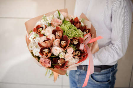 Man in shirt holding a pretty bouquet of flowers on a bright background no faceの写真素材