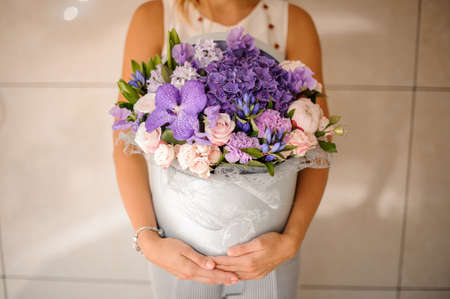 Woman hands with a beautiful purple composition of flowers on a bright background no face close upの写真素材