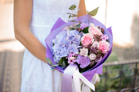 Woman hands holding a pretty wedding bouquet of purple and pink flowers no face close upの写真素材