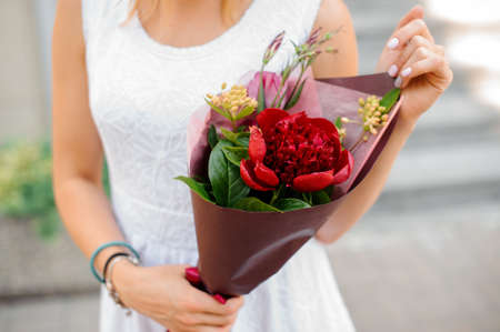 Little combination of colorful flowers in woman hands on the bright background no face close upの写真素材