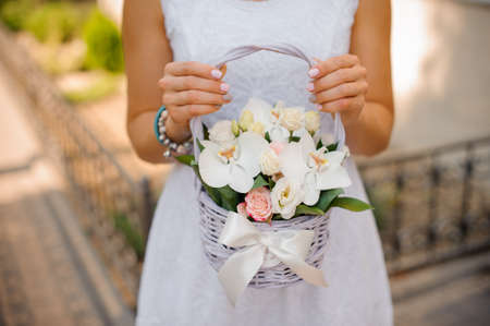 Woman in white dress holding a little wicker basket of flowers no face close upの写真素材