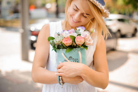 Smiling pretty woman in white dress with a beautiful bouquet of tender flowers close upの写真素材