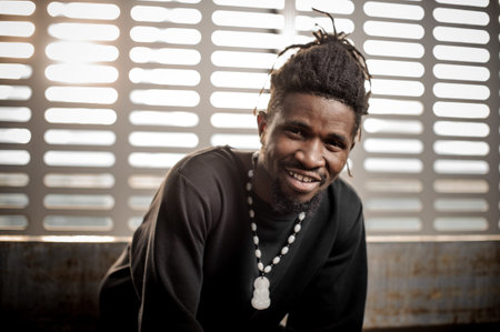 Close up portrait of handsome smiling afro american man in black t-shirt on the background of window