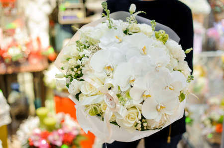 Gorgeous white bouquet of tender and beautiful flowers in woman hands. No face, close up photoの写真素材