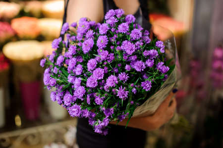 Elegant and beautiful bouquet of little purple flowers in woman hands. No face, close upの写真素材