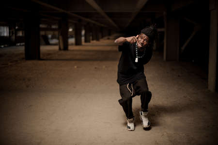 Emotional full length portrait of the gesticulating afro american man with dreadlocks and dressed in black clothesの写真素材