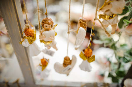 Christmas tree toys in the form of cute little angels hanging on the ropes on the bright backgroundの写真素材