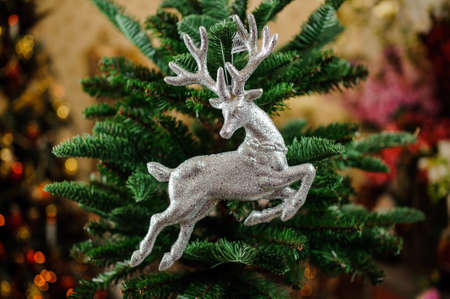 Christmas tree toy in the form of silver deer on the green background of fir treeの写真素材