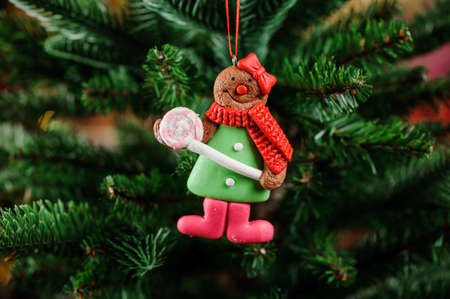 Fine Christmas tree toy in the form of cute alive cookie on the green background of fir treeの写真素材