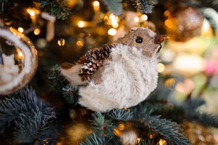 Pretty Christmas tree decoration toy in the form of cute bird on the background of sparkling fir treeの写真素材