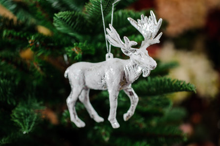 Christmas tree toy in the form of silver moose on the green background of fir treeの写真素材