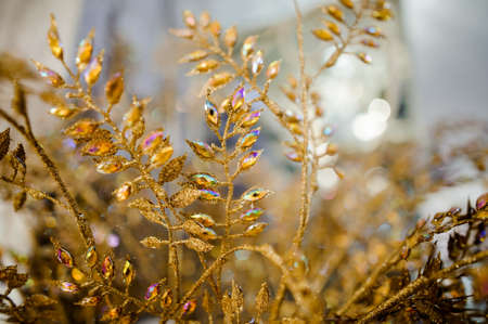 Beautiful Christmas decoration made of golden dried twigs with colorful iridescent rhinestones on the bright backgroundの写真素材