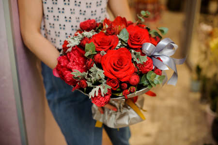 Elegant and stylish red bouquet of beautiful flowers in woman hands. No face, close upの写真素材
