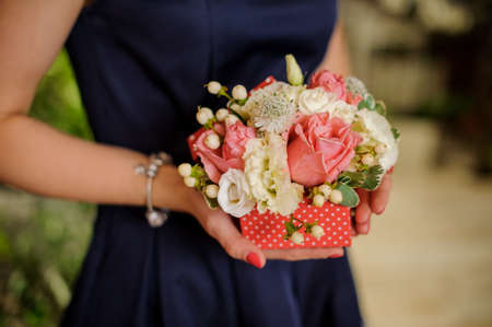 Woman in blue dress is holding a little and tender pink and white flower compositionの写真素材
