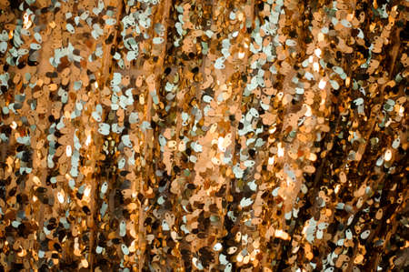 Close up background picture of a lot of metal glittering sequins in golden and silver tonesの写真素材