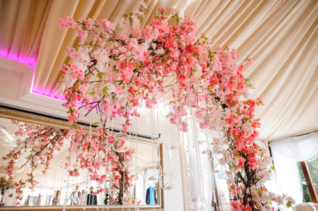 Gorgeous wedding arch decorated with a lot of bright and beautiful pink flowers on the white indoors backgroundの写真素材