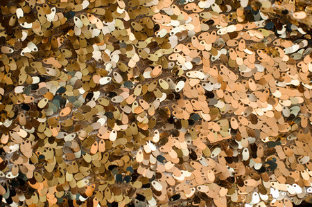 Close up background picture of a lot of glittering sequins in golden and silver tones