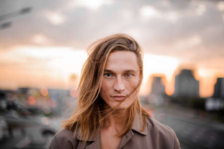 Portrait of young redhead and blue-eyed man on the blurred background of city and sunsetの写真素材