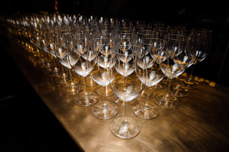 Large set of washed and clean transparent glasses arranged on the wooden table of bar or restaurantの写真素材
