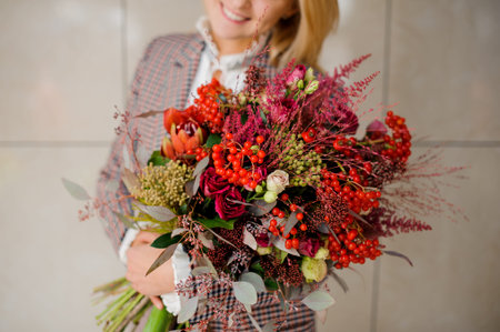 Woman with blonde hair holding a bright bouquet of beautiful and colorful flowers in hands