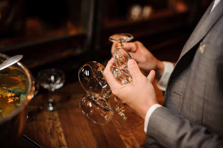 Man in a grey classic suit holding empty glasses for cocktail on the indoors backgroundの写真素材