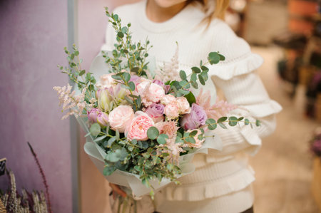 Lovely and tender bouquet of pink and white flowers in woman hands on the light indoors backgroundの写真素材