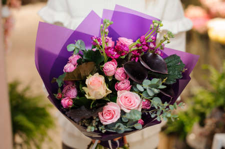 Bright and pretty bouquet of colorful, beautiful flowers in woman hands on the light blurred backgroundの写真素材